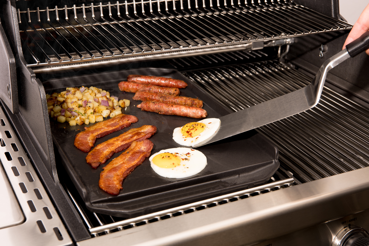 Turner lifting an egg from a cast iron plancha inside a separate grill