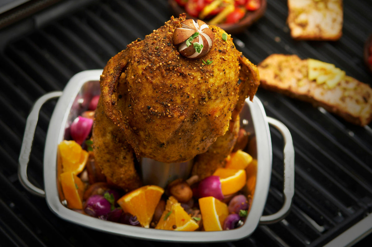 Chicken roasting upright in a square stainless steel pan