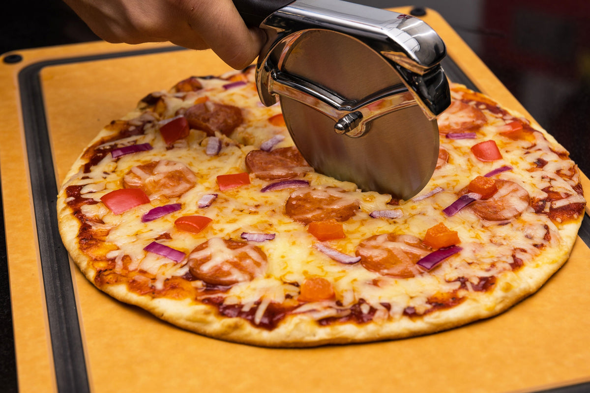 Pizza wheel cutting a topped pizza on a board