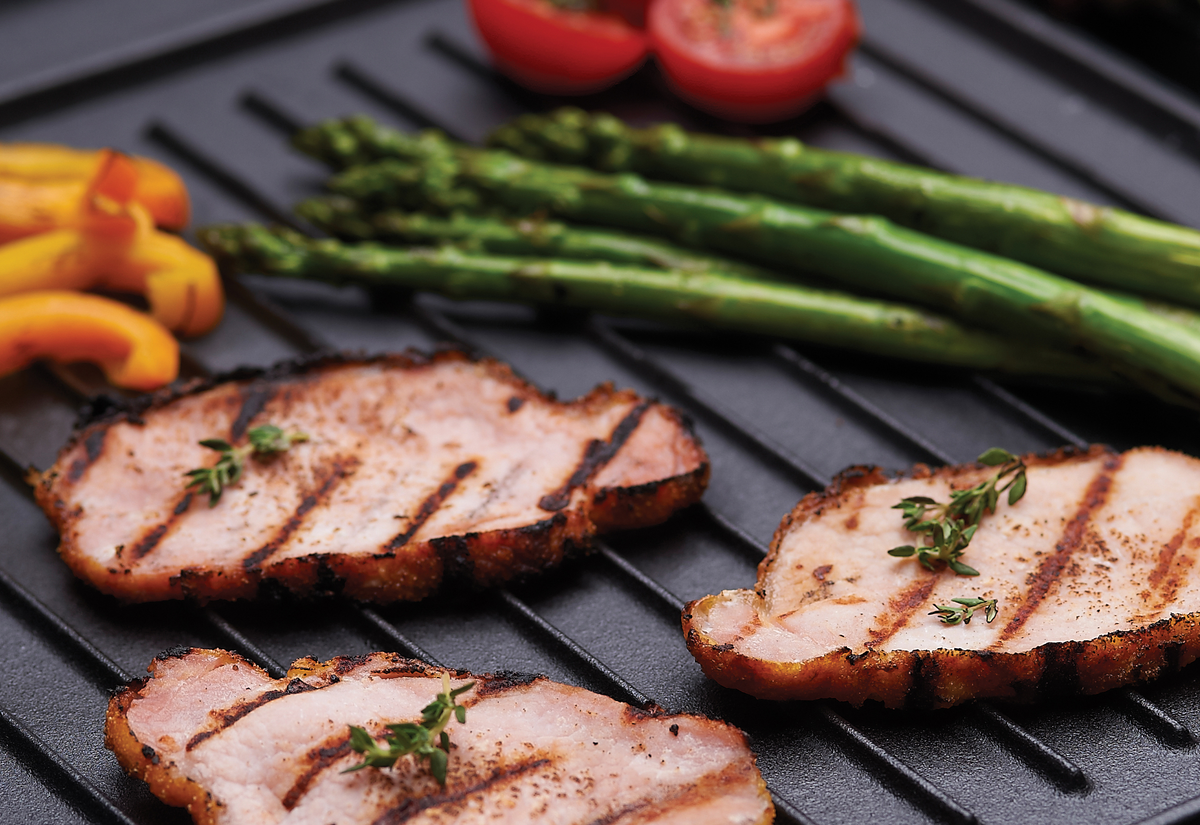 Meat and vegetables cooking on an exact-fit ribbed griddle