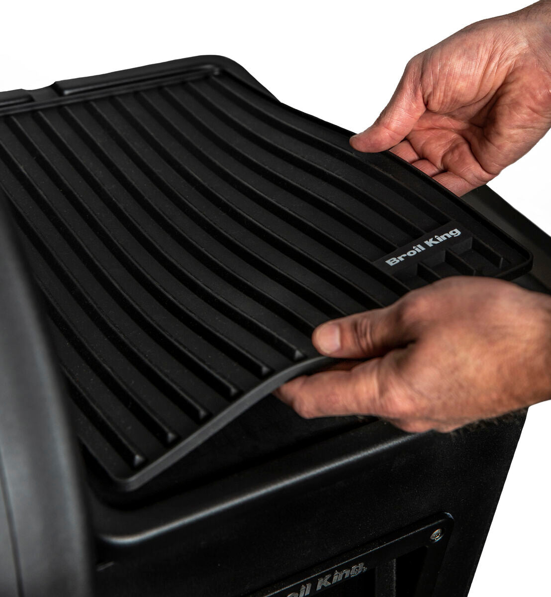 Hands positioning a Regal Pellet magnetic mat on a separate grill shelf