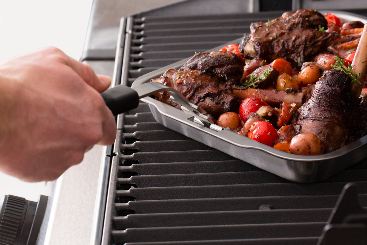 Grid lifter moving a roasting pan containing grilled food
