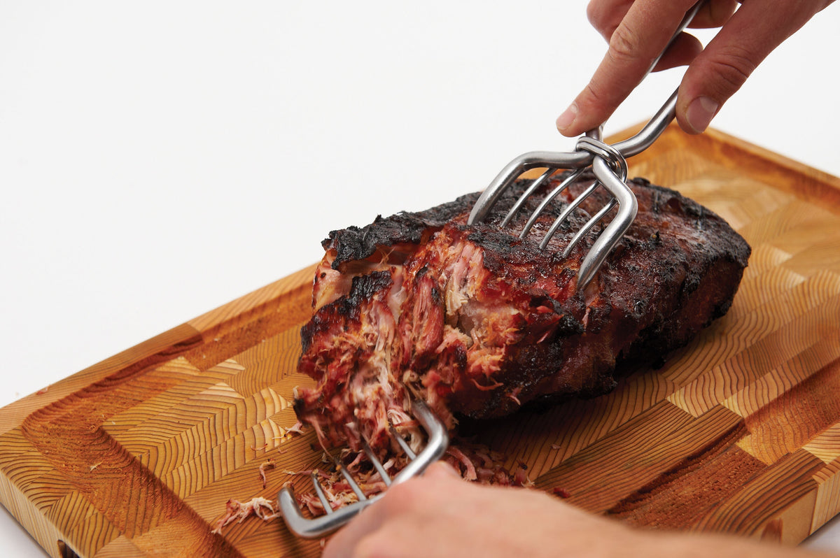 Meat claws holding a roast on a wooden board