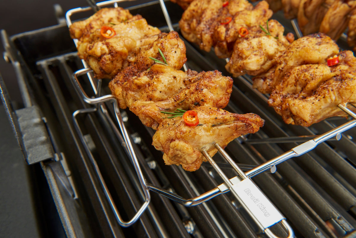 Skewer rack holding chicken kebabs above the cooking grids