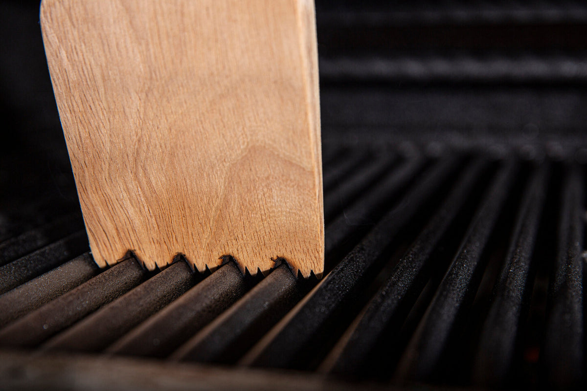 Wood scraper contacting cast iron cooking grids