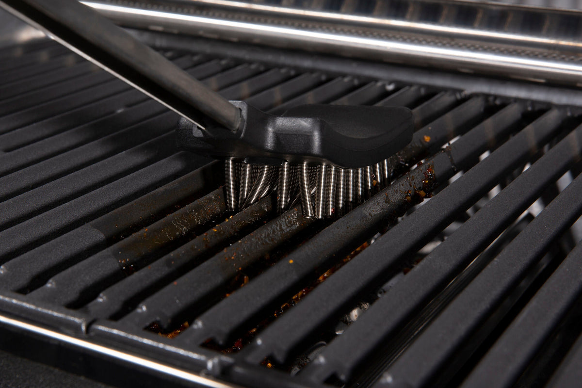 Coil spring brush being used on grill cooking grids