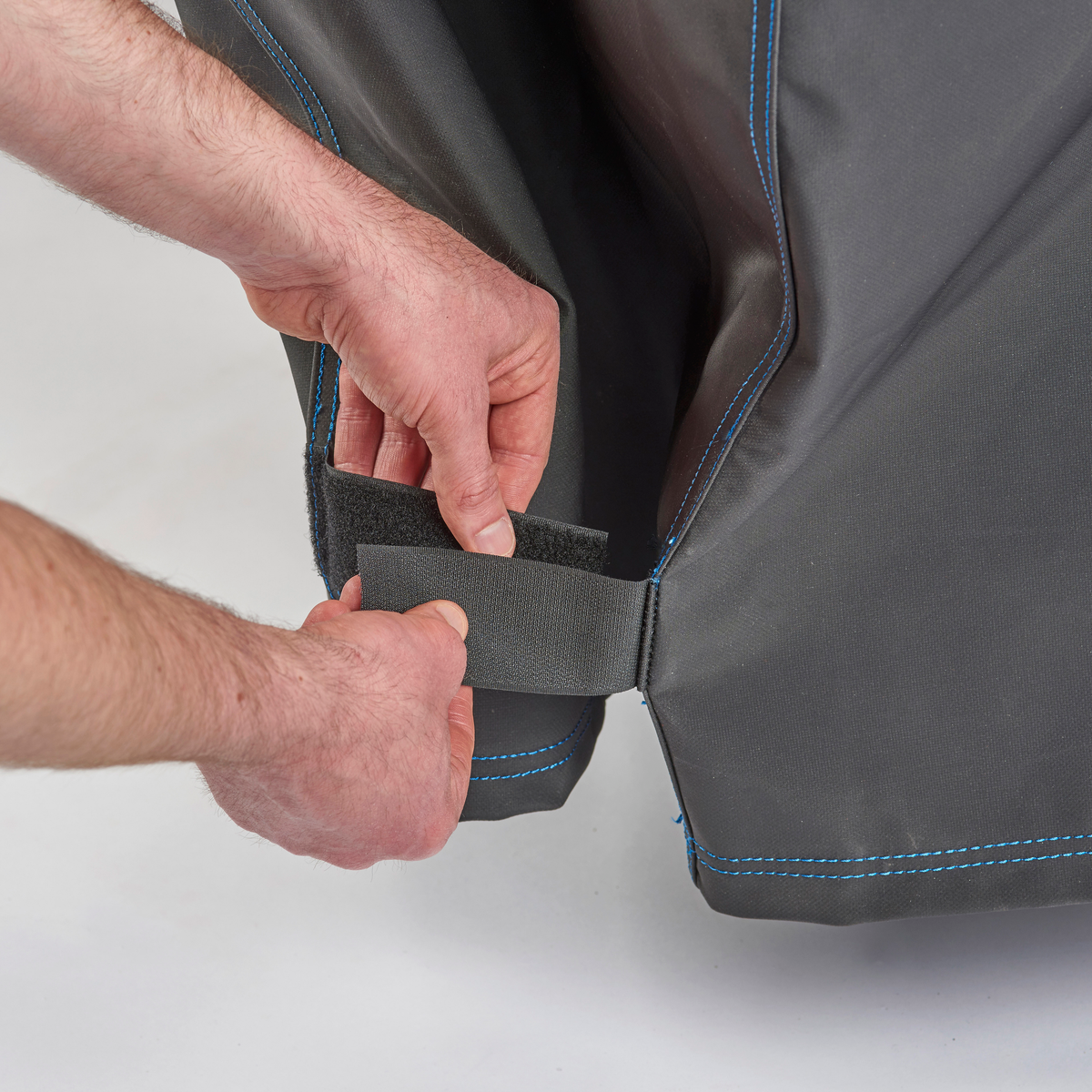 Hands securing the strap of a premium pellet-grill cover