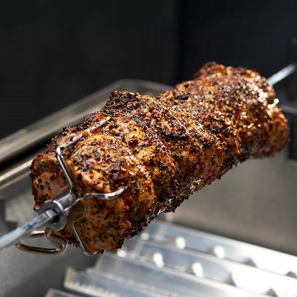 Roast secured on a rotisserie spit inside a separate grill