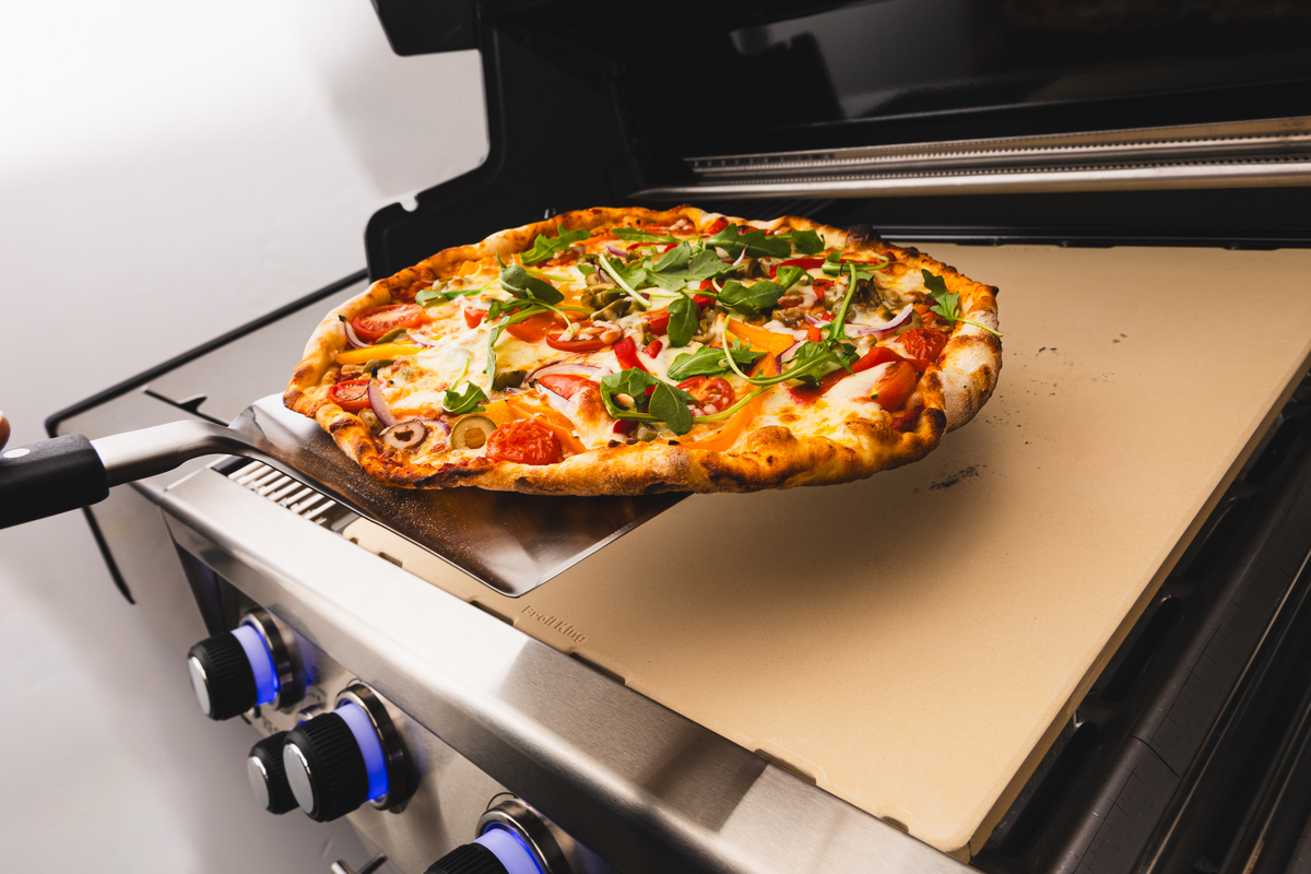 Pizza being lifted from an Imperial and Regal stone inside a separate grill
