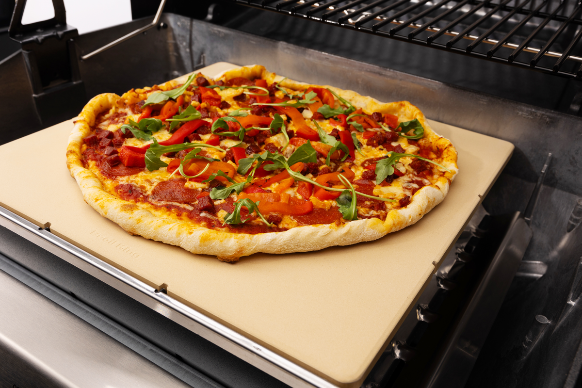 Pizza cooking on a rectangular Monarch and Royal stone inside a separate grill