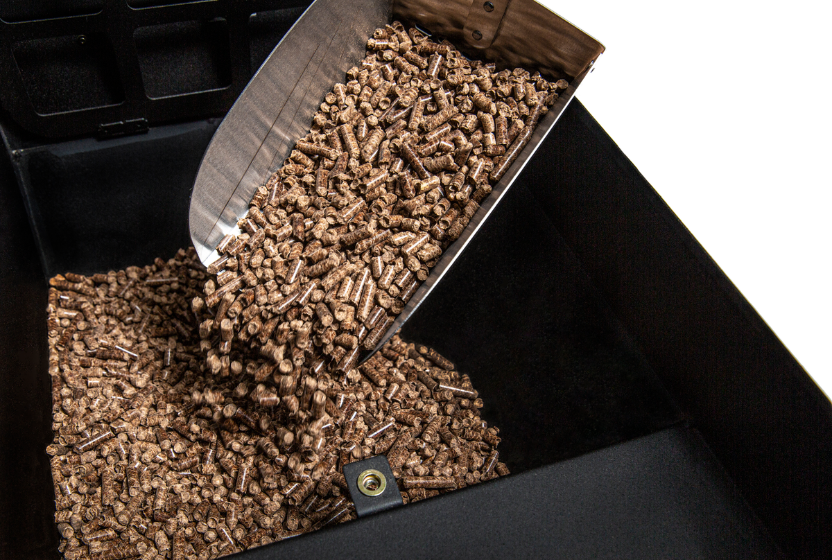 Scoop pouring wood pellets into a grill hopper