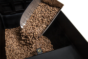 Scoop pouring wood pellets into a grill hopper
