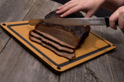 Carving knife slicing cooked brisket on a cutting board