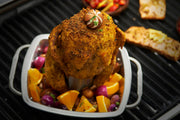 Chicken roasting upright in a square stainless steel pan