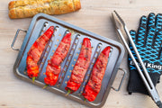 Food skewers arranged on an Imperial stainless steel topper beside separate grilling tools