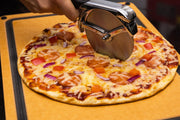 Pizza wheel cutting a topped pizza on a board