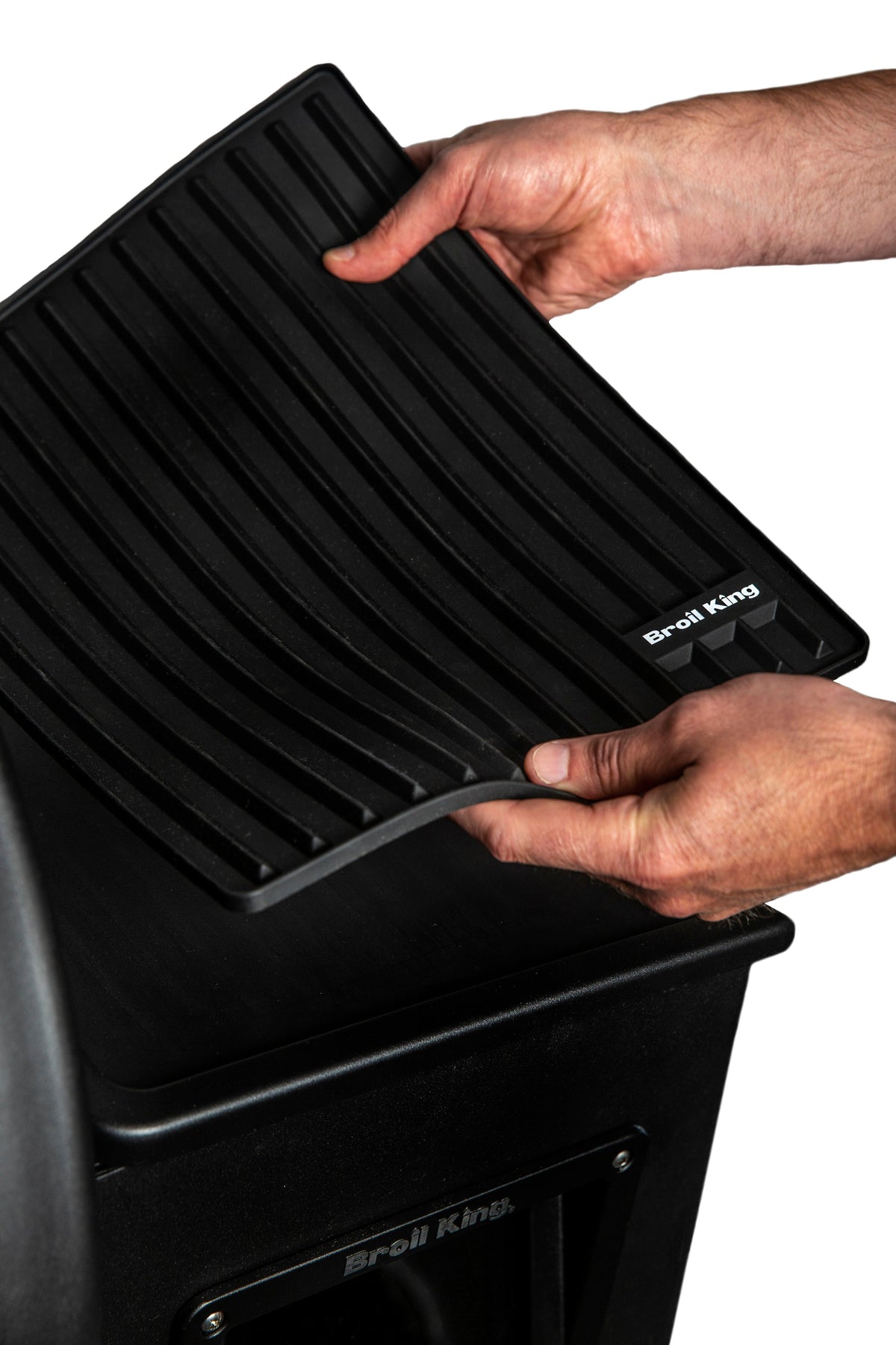 Hands positioning a Crown Pellet magnetic mat on a separate grill shelf