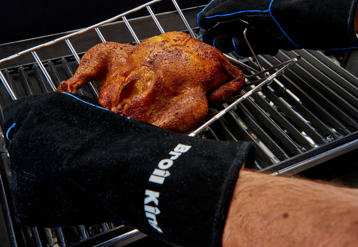Leather grilling gloves handling a rack holding roast chicken