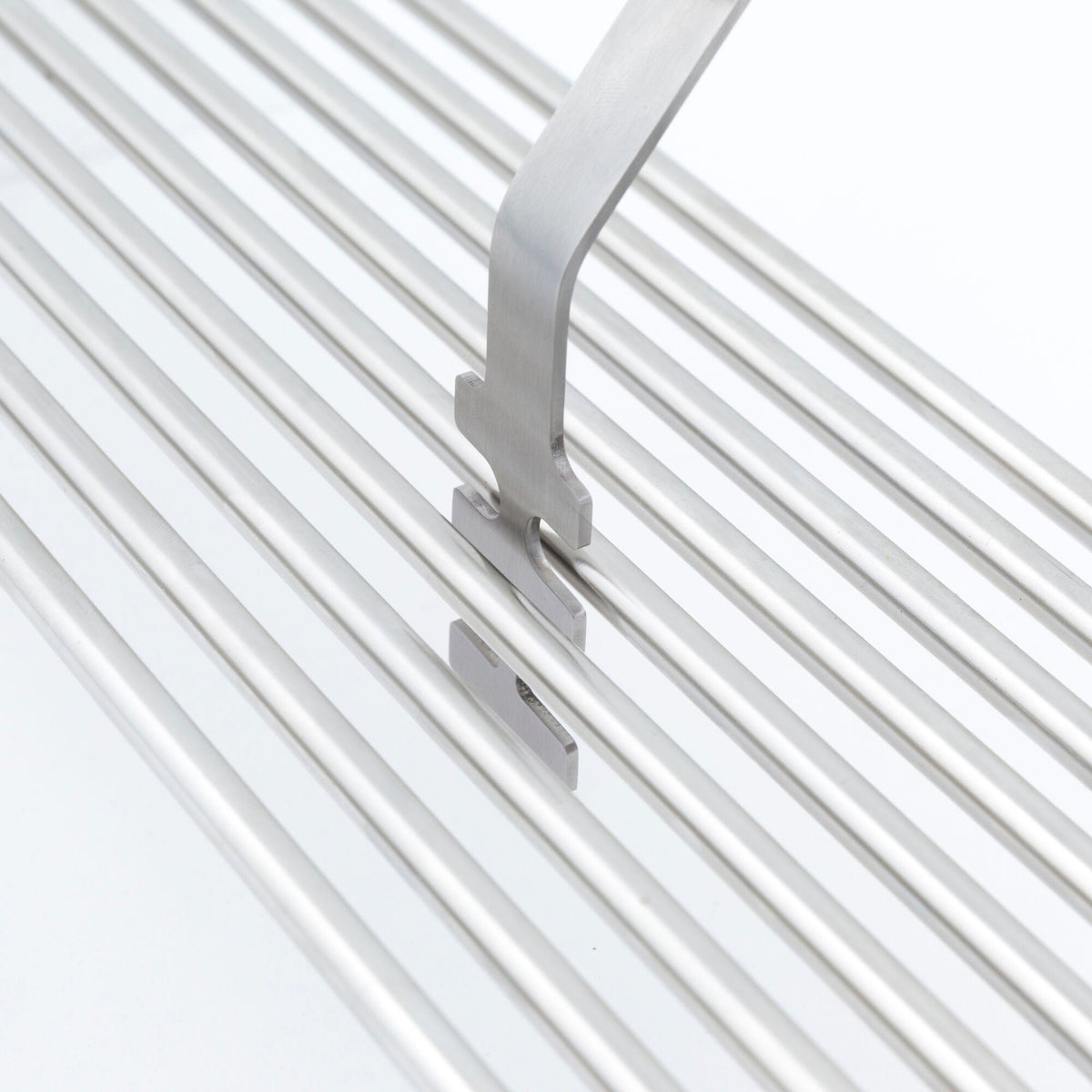 Cooking grid lifter positioned under stainless steel grill rods