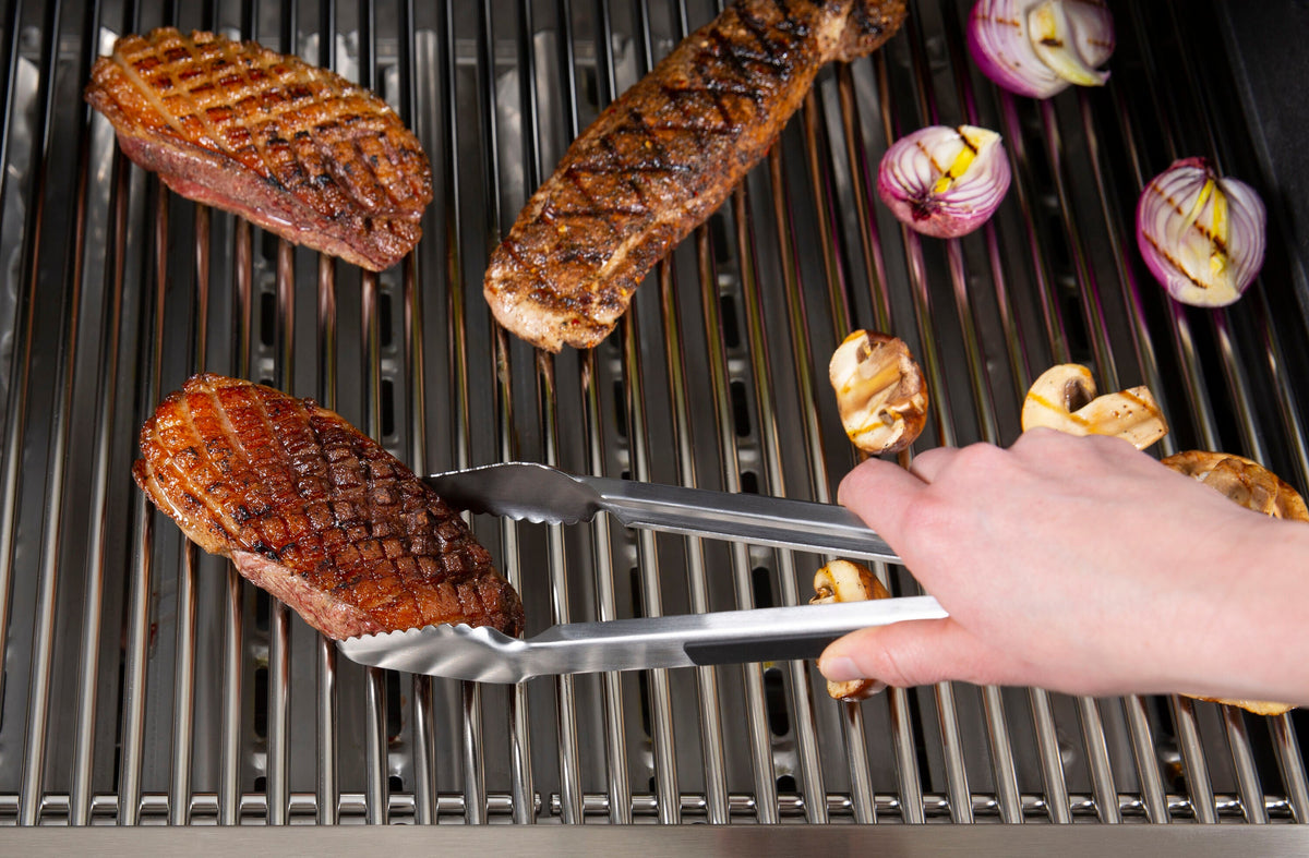 Baron precision tongs being used to turn meat on a grill