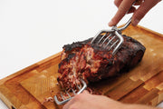 Meat claws holding a roast on a wooden board