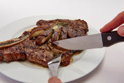 Steak knife cutting a cooked steak on a plate