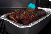 Basting brush applying sauce to ribs in a foil roaster liner
