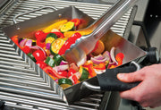 Vegetables being stirred in a deep stainless steel wok on a separate grill