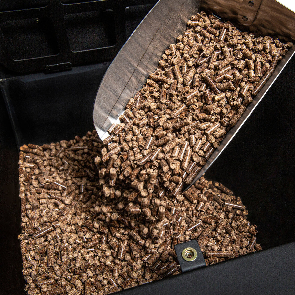Wood pellets being poured into a separate grill hopper