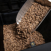 Wood pellets being poured into a separate grill hopper