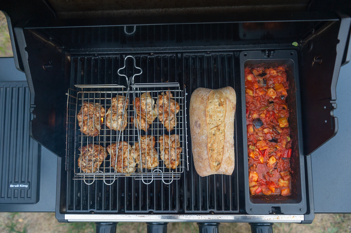 Cast iron wok cooking vegetables beside other separate grilling accessories