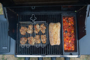 Cast iron wok cooking vegetables beside other separate grilling accessories