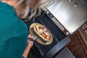 Pizza cooking on a ceramic stone inside a separate grill
