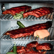 Ribs and vegetables arranged on cabinet-smoker cooking grids