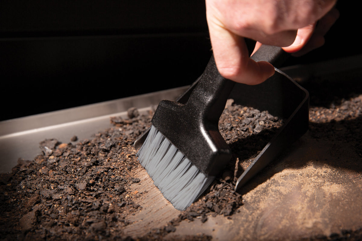 Ash sweeping brush being used to gather ash
