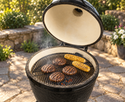 Primo Round charcoal grill with burgers and corn on the cooking grate